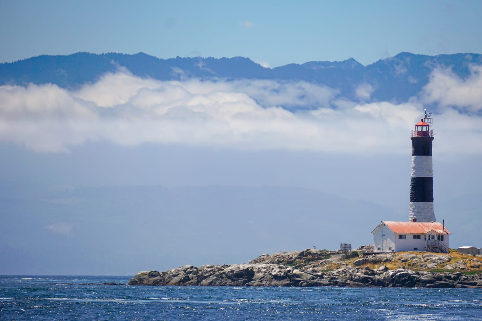 Race Rocks Lighthouse on a rocky island with misty mountains
